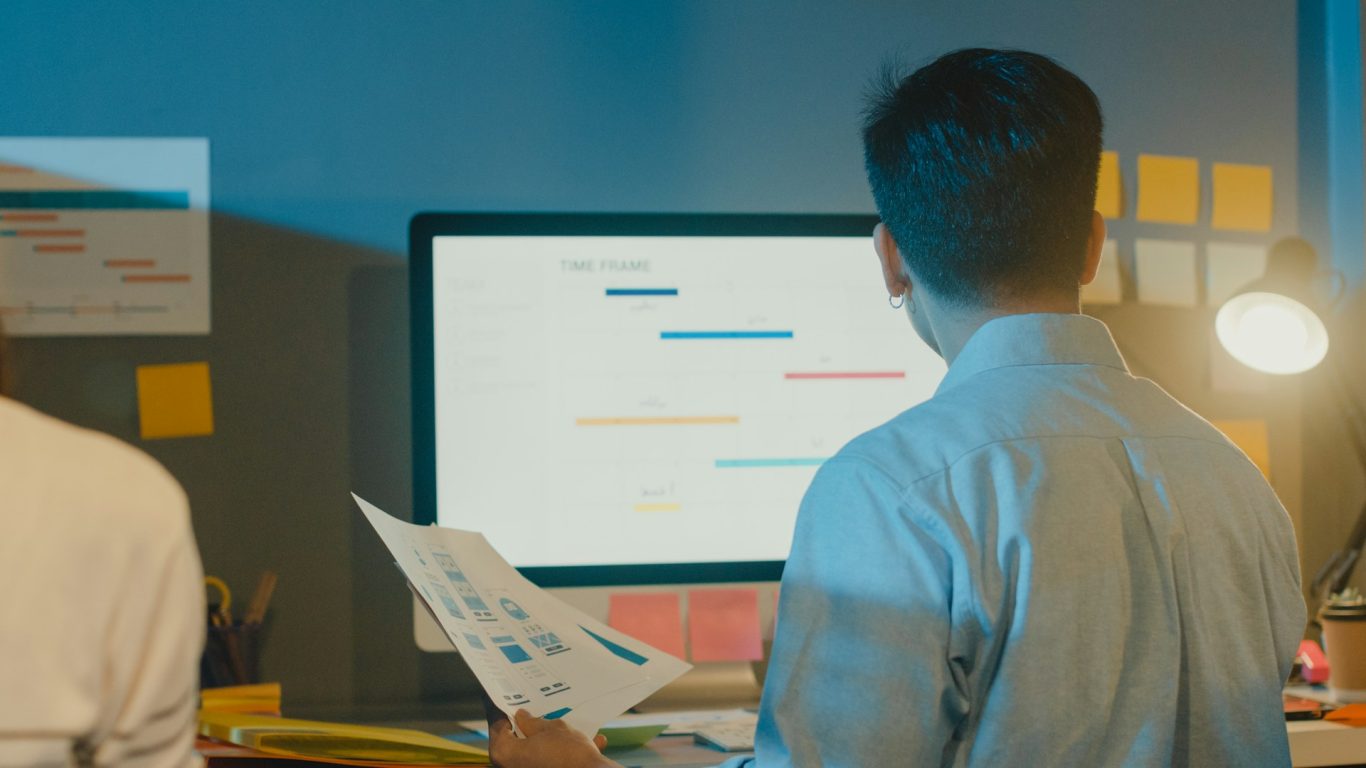 Så går ett uppdrag till Personer som diskuterar arbetsdiagram framför en dator med färgglada anteckningar i bakgrunden.